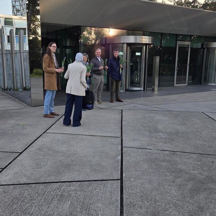 Deelnemers aan de actie staan met bossen irissen bij de bezoekersingang van het Internationaal Strafhof