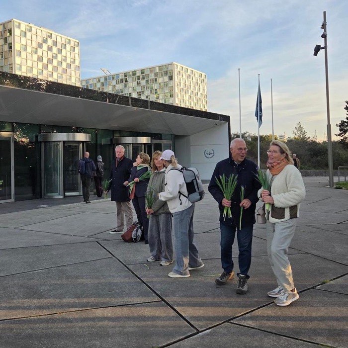 Een groep deelnemers met irissen loopt over het plein voor het Internationaal Strafhof